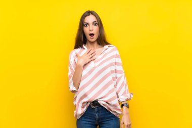 İzole edilmiş sarı arka planı olan genç bir kadın sağa bakarken şaşırmış ve şok olmuştu.