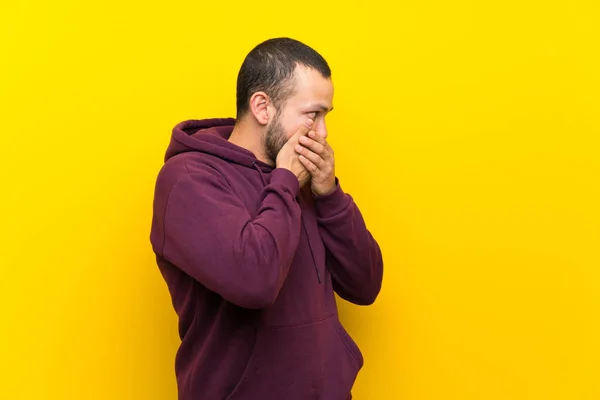 Hombre Colombiano Con Sudadera Sobre Pared Amarilla Cubriendo Boca Mirando —  Fotos de Stock