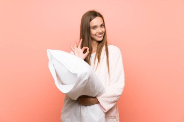 Pembe duvar üzerinde sabahlık genç kadın parmakları ile ok işareti gösteren