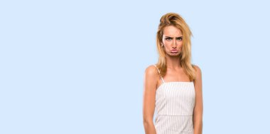 Izole mavi arka plan üzerinde üzgün ve depresif ifade ile Genç sarışın kadın