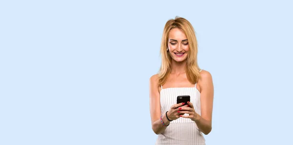 Young Blonde Woman Sending Message Mobile Isolated Blue Background — Stock Photo, Image