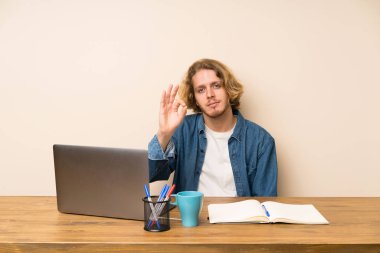 Parmaklar ile bir ok işareti gösteren bir laptop ile sarışın adam