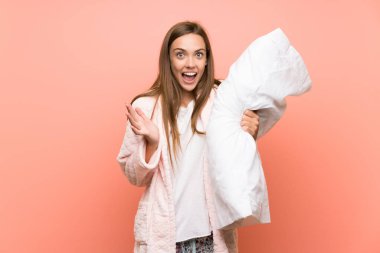 Sürpriz yüz ifadesi ile pembe duvar üzerinde sabahlık genç kadın