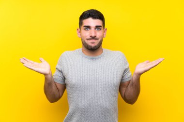 Izole sarı arka plan üzerinde genç yakışıklı adam yüz ifadesi karıştırmayın ile şüpheleri olan