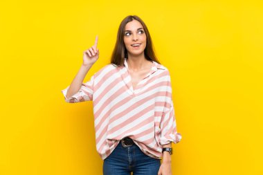 Sarı arka plan izole edilmiş genç bir kadın parmağını kaldırarak çözümü anlamaya çalışıyor.