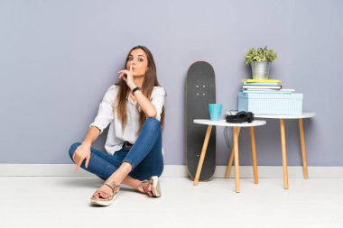 Yerde oturan genç kadın sessizlik jesti yapıyor