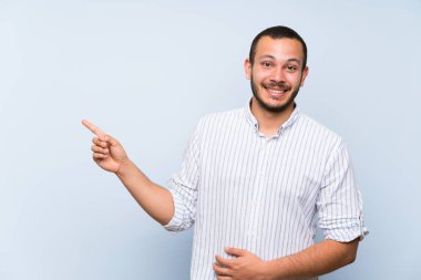 Izole mavi duvar tarafında parmak işaret üzerinde Kolombiyalı adam
