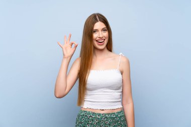 Izole mavi arka plan üzerinde genç kadın şaşırttı ve ok işareti gösteren