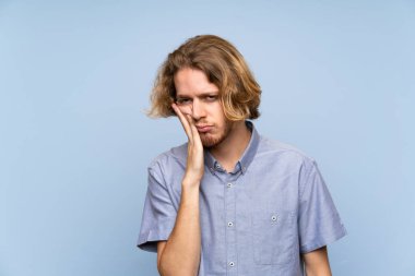 Izole mavi duvar üzerinde Sarışın adam mutsuz ve sinirli