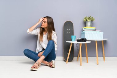 Genç bayan yerde oturmuş gülüyor.