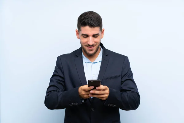 Hombre Guapo Sobre Fondo Azul Aislado Enviando Mensaje Con Móvil —  Fotos de Stock