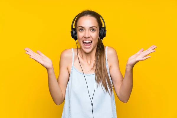 Νεαρή Γυναίκα Ακούγοντας Μουσική Πάνω Από Απομονωμένο Κίτρινο Τοίχο Σοκαρισμένοι — Φωτογραφία Αρχείου