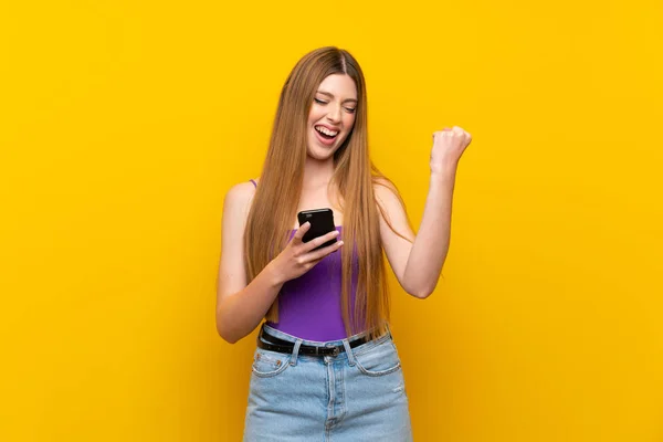 Mujer Joven Sobre Fondo Amarillo Aislado Con Teléfono Posición Victoria —  Fotos de Stock