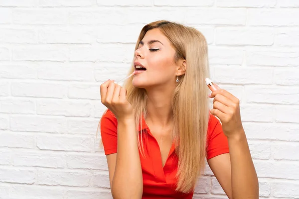 Tonåring flicka med kosmetiska över tegelvägg — Stockfoto