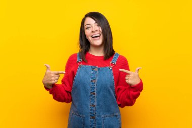 Sarı duvar üzerinde tulum ile genç Meksikalı kadın gurur ve kendini tatmin