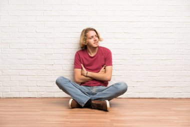 Sarışın adam kolları çapraz ve mutlu ile katta oturan