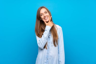 Izole mavi arka plan üzerinde genç kadın gülümseyerek