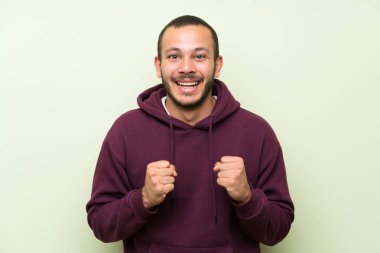 Bir zafer kutluyor yeşil duvar üzerinde Sweatshirt ile Kolombiyalı adam