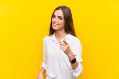 İzole sarı arka plan üzerinde genç kadın size parmak