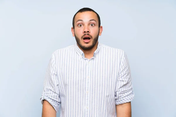 Stock image Colombian man over isolated blue wall with surprise facial expression