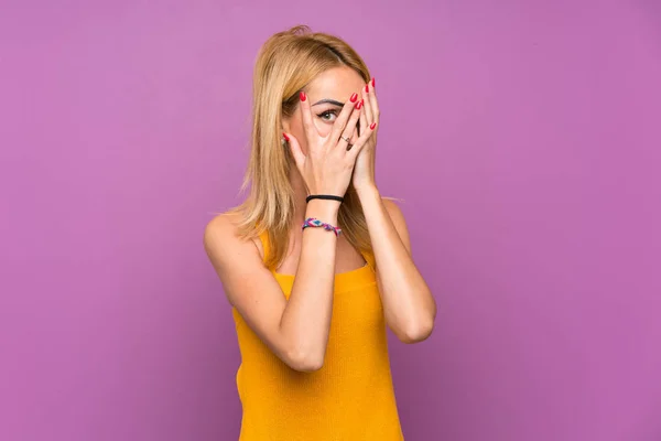 Mujer Rubia Joven Sobre Fondo Púrpura Cubriendo Los Ojos Mirando —  Fotos de Stock