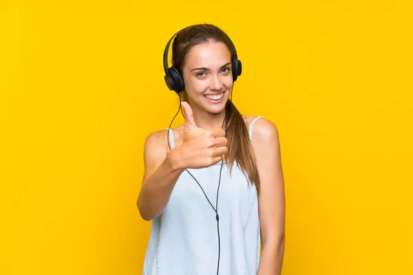 Νεαρή Γυναίκα Ακούγοντας Μουσική Πάνω Από Απομονωμένο Κίτρινο Τοίχο Αντίχειρες — Φωτογραφία Αρχείου
