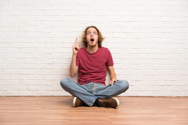 Blonde Man Zittend Vloer Wijzend Verrast — Stockfoto