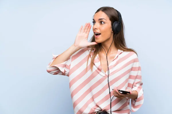 Mujer Joven Escuchando Música Con Móvil Sobre Una Pared Azul —  Fotos de Stock