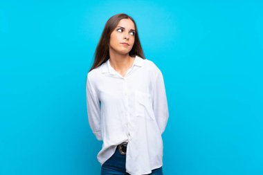 Soyutlanmış mavi arka planda genç bir kadın şüpheli hareketler yapıyor.