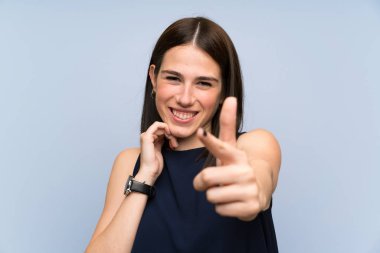 Izole mavi duvar üzerinde genç kadın size parmak