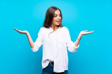 İki eliyle copyspace tutan izole mavi arka plan üzerinde genç kadın