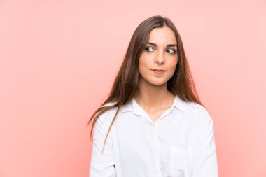 Izole pembe arka plan ayakta ve yan bakarak genç kadın