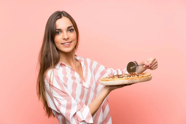 Молодая Женщина Держит Пиццу Над Изолированной Розовой Стеной — стоковое фото