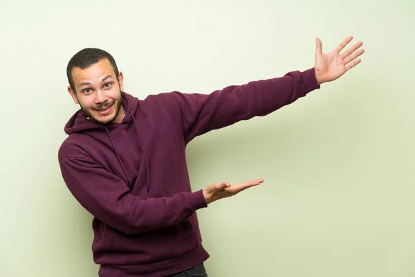 Colombiaanse Man Met Sweatshirt Groene Muur Uitbreiding Van Handen Naar — Stockfoto