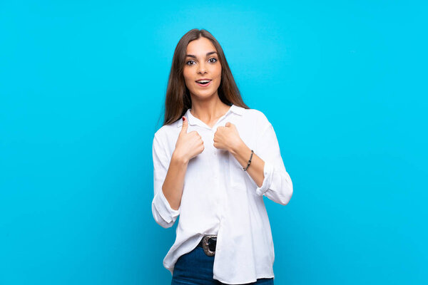 Молодая женщина на изолированном синем фоне с неожиданным выражением лица