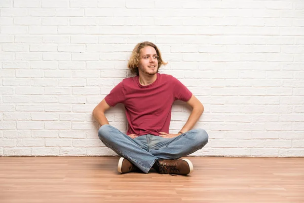 Homem Loiro Sentado Chão Posando Com Braços Quadril Sorrindo — Fotografia de Stock
