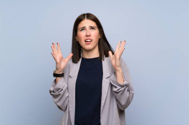 Izole mavi duvar üzerinde genç kadın kötü bir durum tarafından sinirli