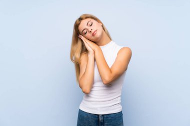 İzole edilmiş mavi arka planda yorgun ve hasta bir yüzü olan genç kız.