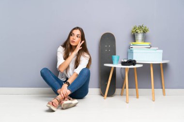 Yerde oturan genç kadın bir şeyler fısıldıyor.