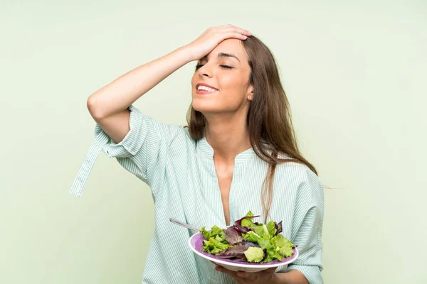 年轻女子与沙拉在孤立的绿色墙壁已经意识到的东西 并打算解决 — 图库照片