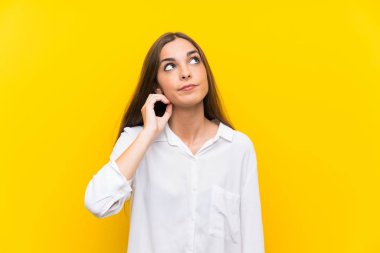 Izole sarı arka plan üzerinde genç kadın bir fikir düşünme