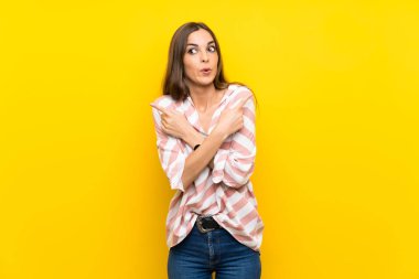 İzole edilmiş sarı arka planda genç bir kadın. Yan taraftakilerin şüpheleri var.