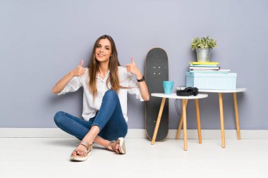 Genç kadın yere oturmuş bir başparmak kadar jest vererek