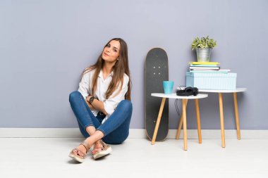 Genç bayan yerde oturmuş gülüyor.