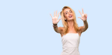 Genç sarışın kadın izole mavi arka plan üzerinde parmakları ile sekiz sayma