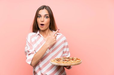 İzole pembe duvar üzerinde pizza tutan genç kadın şaşırttı ve yan işaret