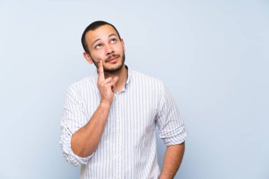 Kolombiyalı adam izole mavi duvar üzerinde bakarken bir fikir düşünme