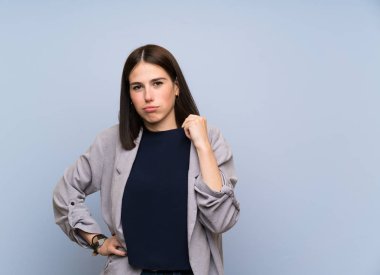 Yorgun ve hasta ifade ile izole mavi duvar üzerinde genç kadın