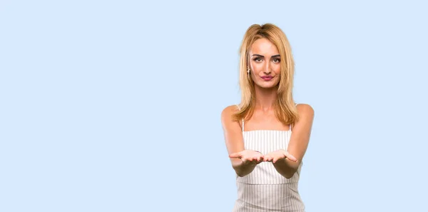 年轻的金发女人拿着复制空间假想在手掌上插入一个广告在孤立的蓝色背景 — 图库照片
