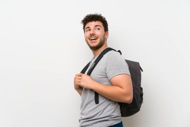 Sırt çantası ile izole duvar üzerinde kıvırcık saçlı Adam